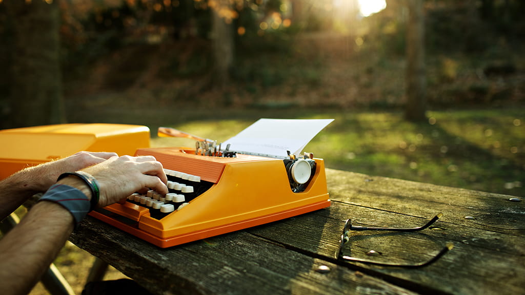 Hands on the orange typewriter in a park