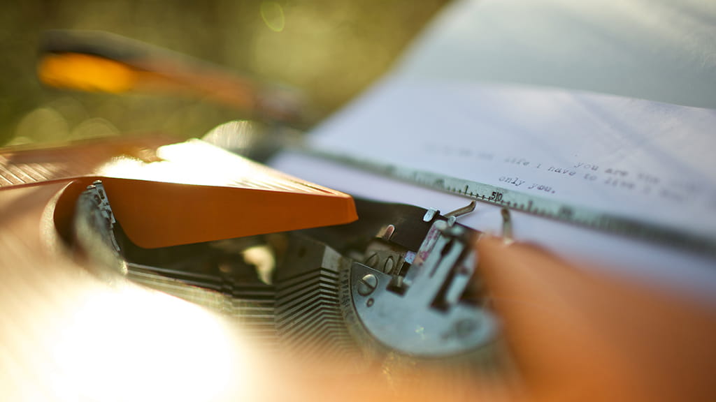 Orange typewriter on a wooden table close-up